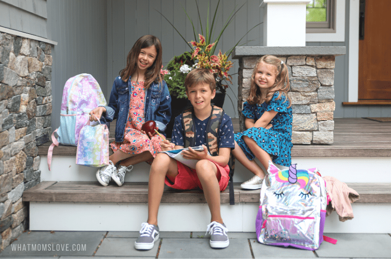 3 kids sitting on steps on first day of school