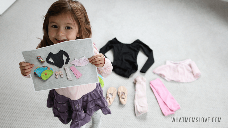 young girl holding up photo of clothes as if getting ready to pack a bag