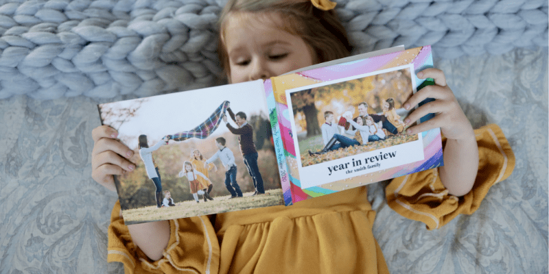 girl lying down looking at family year in review photo book