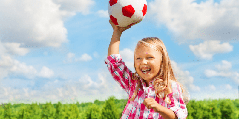 girl laughing holding soccer ball