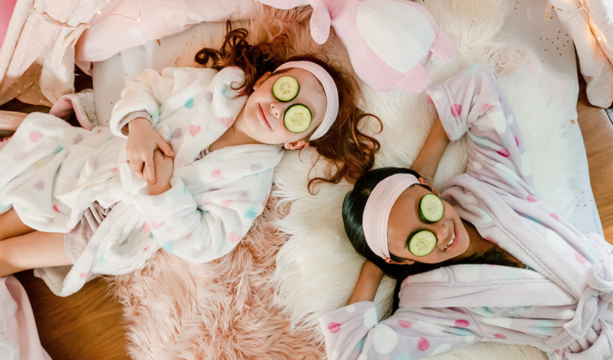 2 girls at sleepover with robes and cucumbers on their eyes